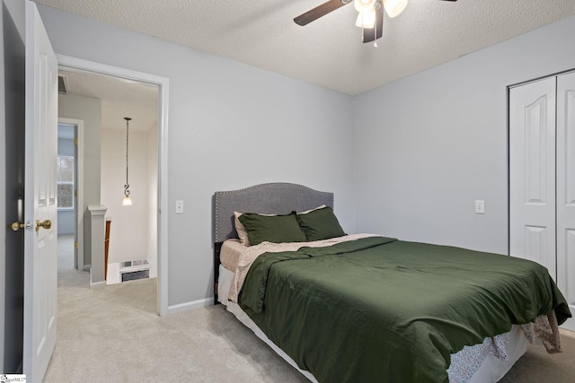 carpeted bedroom with ceiling fan, a textured ceiling, and a closet