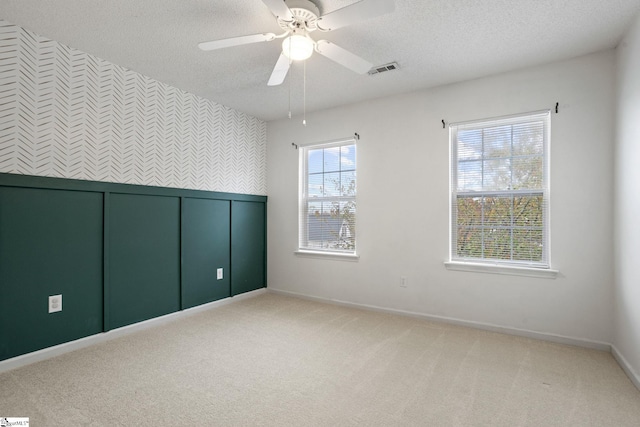 carpeted empty room featuring ceiling fan and a textured ceiling