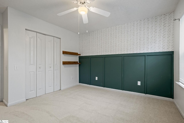 unfurnished bedroom with light colored carpet, a closet, and ceiling fan