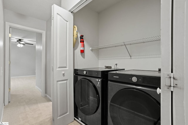 clothes washing area featuring light carpet, a textured ceiling, washer and clothes dryer, and ceiling fan