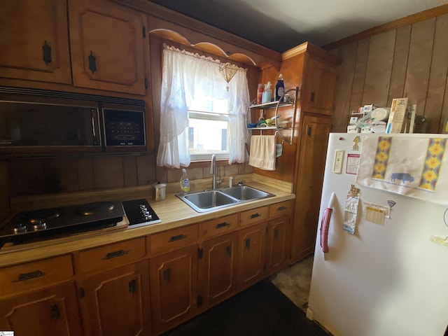 kitchen with sink, wooden walls, and white fridge