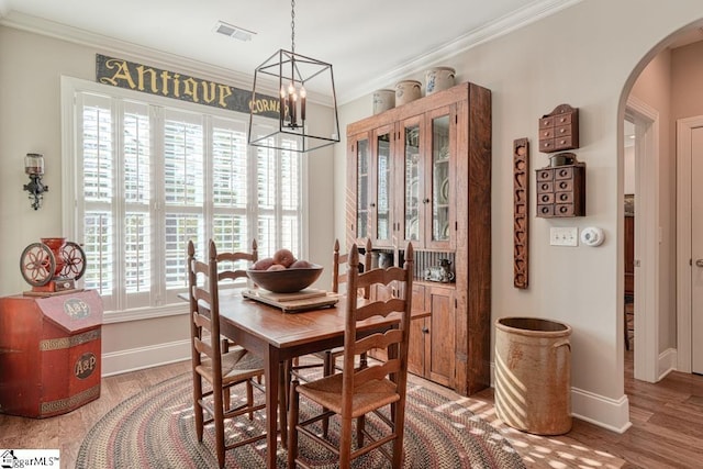 dining area featuring a notable chandelier, crown molding, a wealth of natural light, and hardwood / wood-style flooring