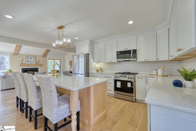 kitchen featuring stainless steel appliances, an island with sink, and white cabinets