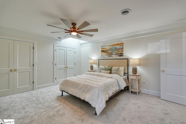 carpeted bedroom featuring ceiling fan, ornamental molding, and multiple closets