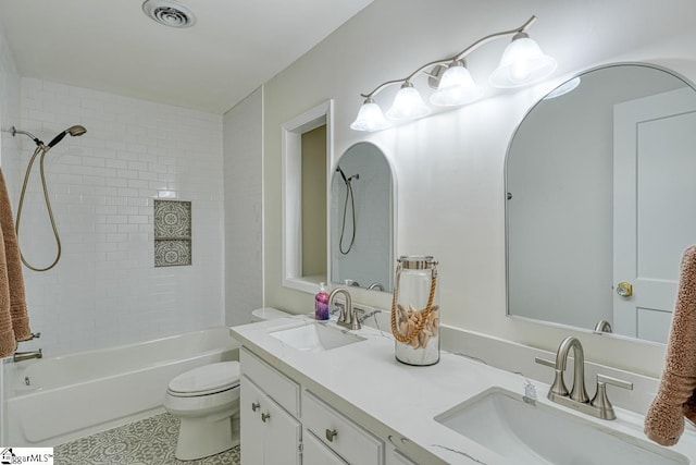 full bathroom with tiled shower / bath, vanity, and toilet