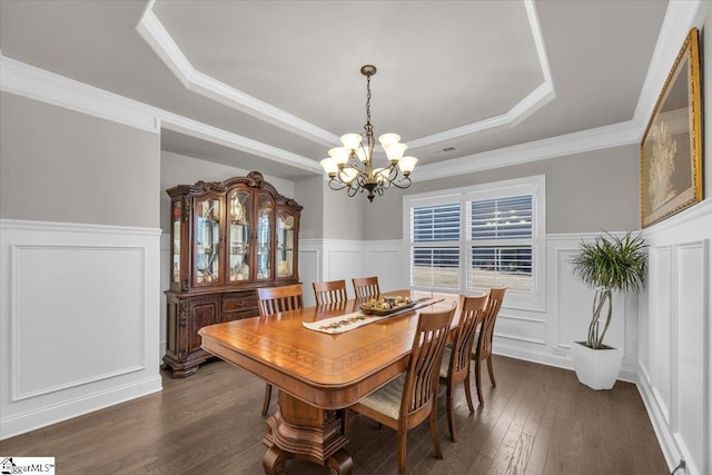 dining area featuring ornamental molding, dark hardwood / wood-style floors, a chandelier, and a tray ceiling