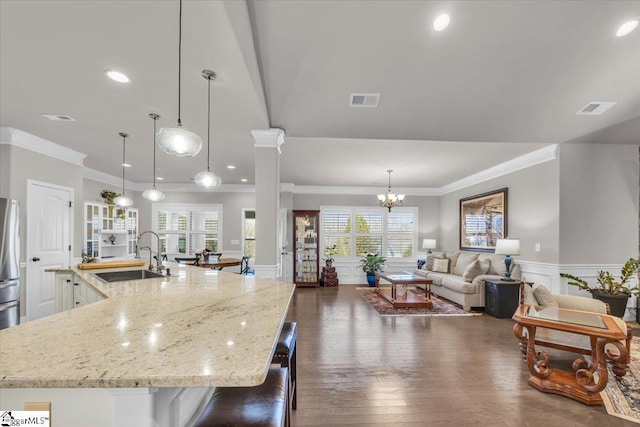 kitchen featuring sink, decorative light fixtures, light stone countertops, and a spacious island