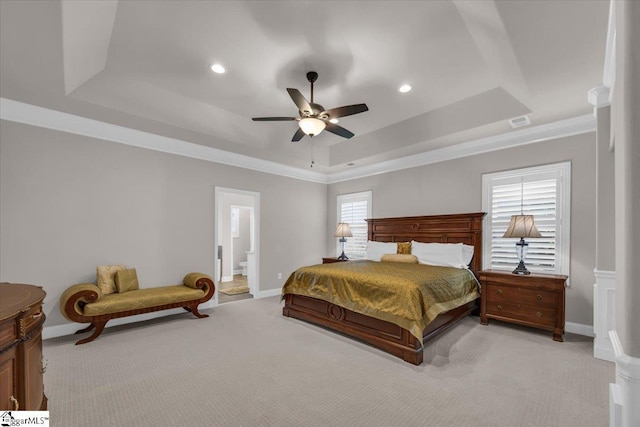 carpeted bedroom with crown molding, a raised ceiling, ceiling fan, and ensuite bathroom