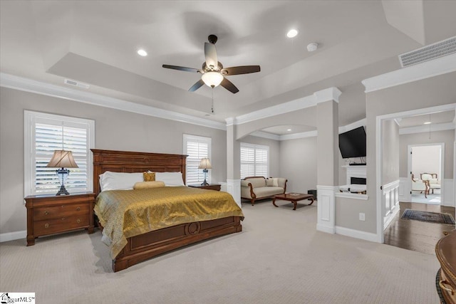 bedroom featuring ceiling fan, ornamental molding, a tray ceiling, and light carpet