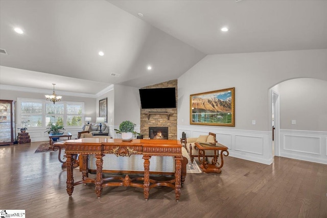 dining room with an inviting chandelier, a stone fireplace, dark hardwood / wood-style flooring, and vaulted ceiling