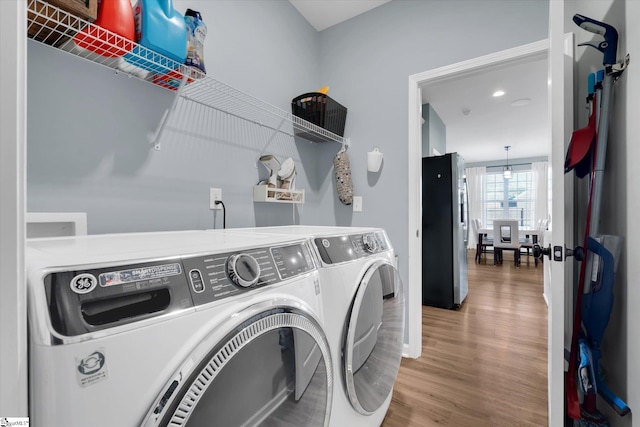 clothes washing area with hardwood / wood-style flooring and washing machine and clothes dryer