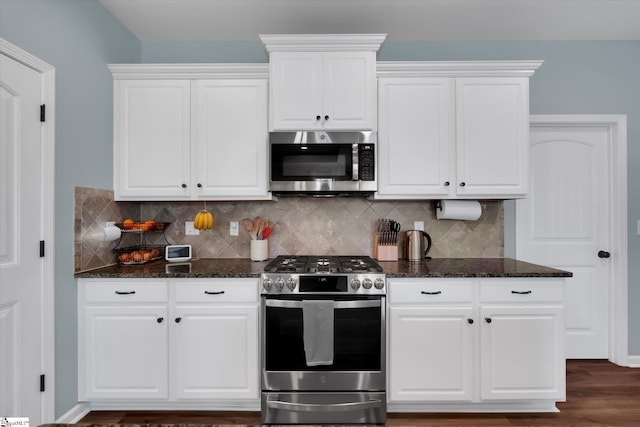 kitchen with white cabinetry, appliances with stainless steel finishes, and dark stone counters