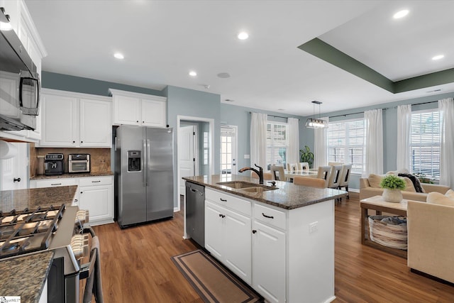 kitchen featuring decorative light fixtures, an island with sink, sink, white cabinets, and stainless steel appliances