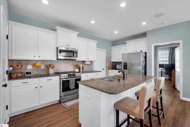 kitchen featuring sink, dark wood-type flooring, appliances with stainless steel finishes, an island with sink, and white cabinets