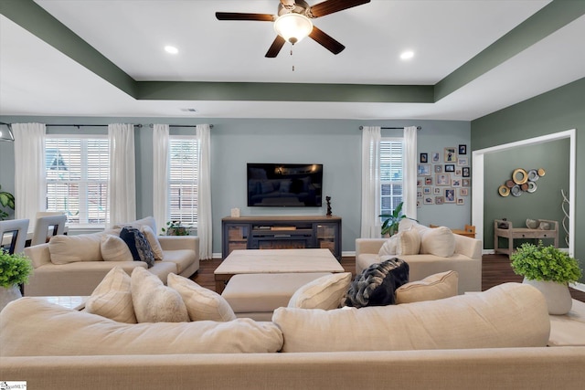 living room with a tray ceiling, wood-type flooring, and ceiling fan