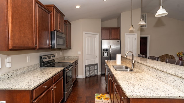 kitchen with a kitchen bar, sink, appliances with stainless steel finishes, pendant lighting, and a kitchen island with sink