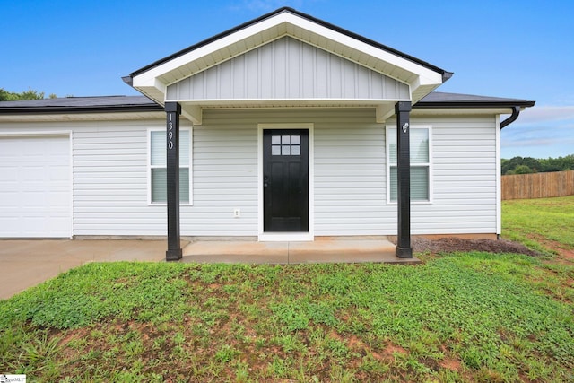 entrance to property with a garage and a lawn