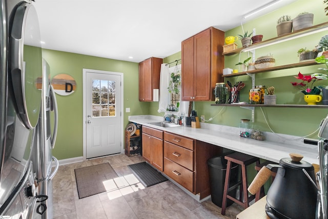 kitchen featuring light stone counters, stainless steel fridge, and sink