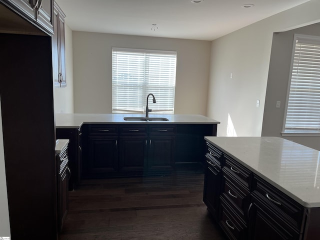 kitchen with dark hardwood / wood-style flooring, sink, and light stone countertops