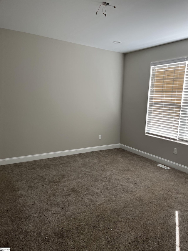 unfurnished room with dark carpet