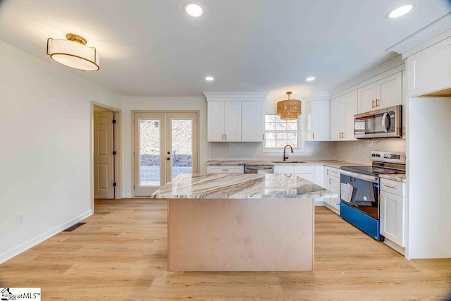 kitchen with sink, a center island, stainless steel appliances, light stone countertops, and white cabinets