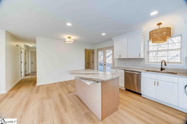 kitchen with pendant lighting, dishwasher, sink, white cabinets, and light stone countertops