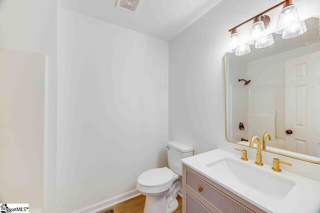 bathroom with vanity, hardwood / wood-style floors, walk in shower, and toilet