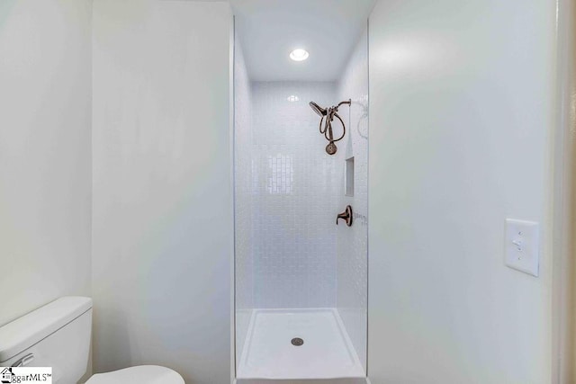bathroom featuring tiled shower and toilet
