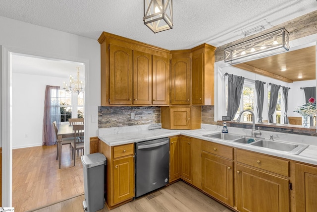 kitchen with dishwasher, sink, backsplash, light hardwood / wood-style floors, and a textured ceiling