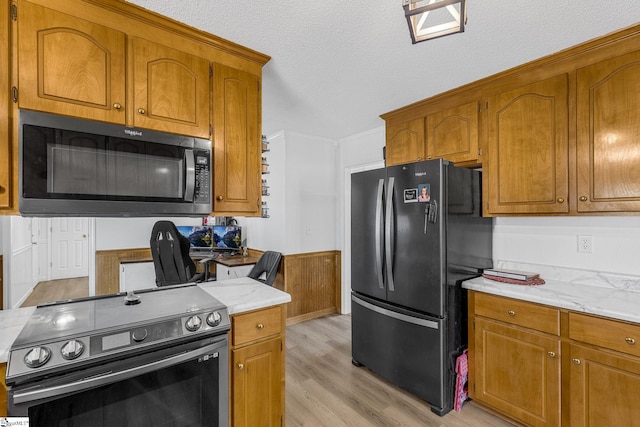 kitchen with black refrigerator, a textured ceiling, electric range, and light wood-type flooring