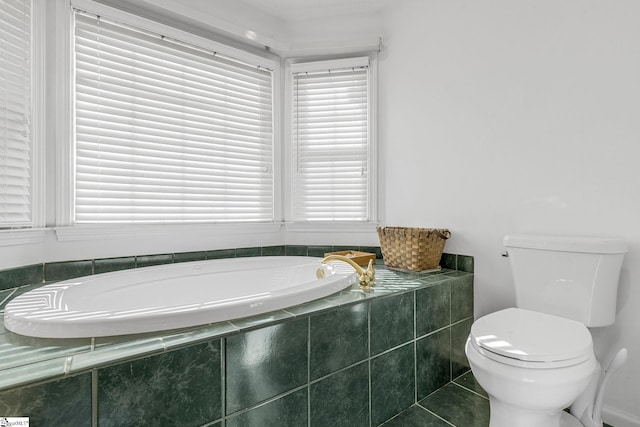 bathroom with a relaxing tiled tub, tile patterned floors, and toilet