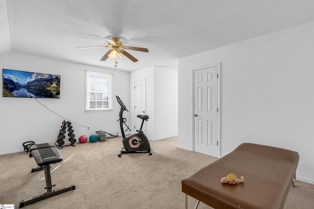 exercise room with ceiling fan, light colored carpet, and a textured ceiling