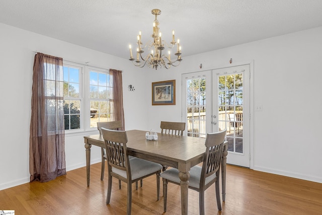 dining room featuring a healthy amount of sunlight, wood-type flooring, and a textured ceiling