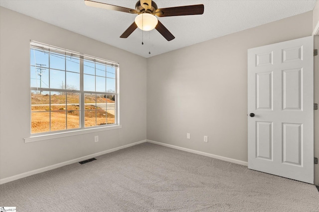 carpeted spare room with ceiling fan and a textured ceiling