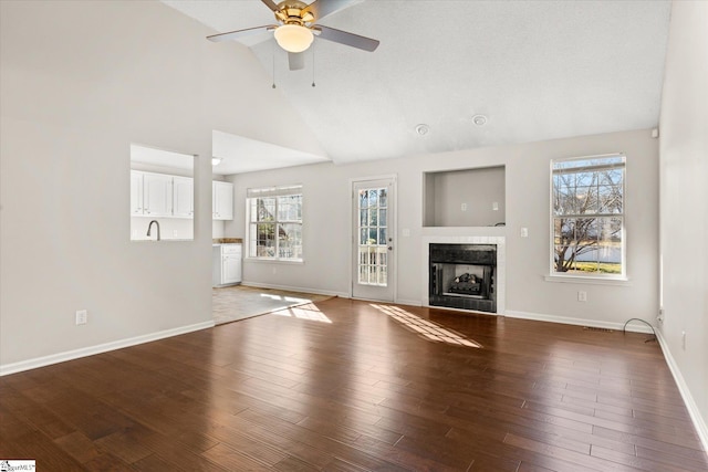 unfurnished living room with hardwood / wood-style flooring, high vaulted ceiling, and ceiling fan