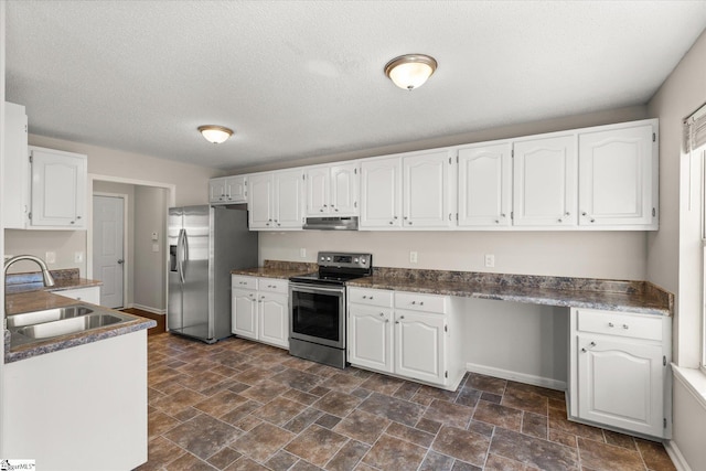 kitchen with sink, white cabinetry, stainless steel appliances, built in desk, and a textured ceiling