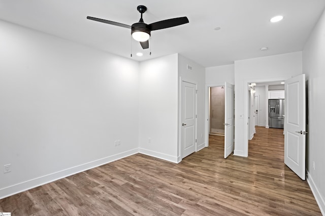 unfurnished bedroom with hardwood / wood-style flooring, stainless steel fridge, and ceiling fan