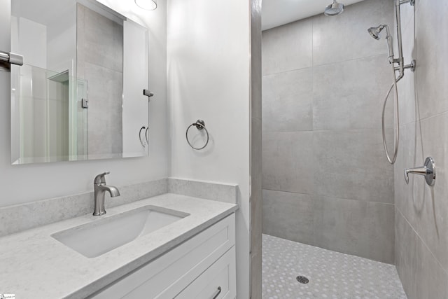 bathroom with a tile shower and vanity