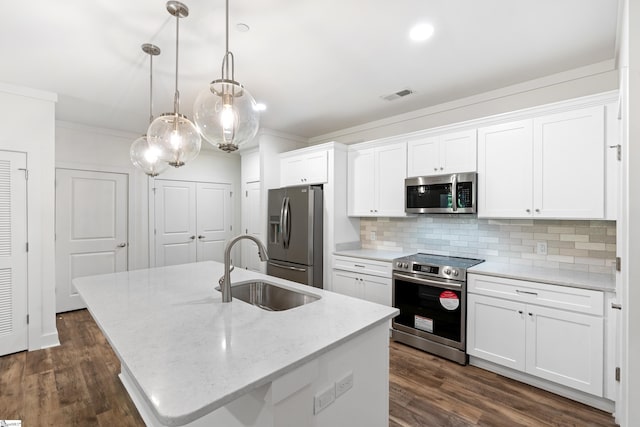 kitchen featuring sink, appliances with stainless steel finishes, white cabinetry, hanging light fixtures, and a center island with sink