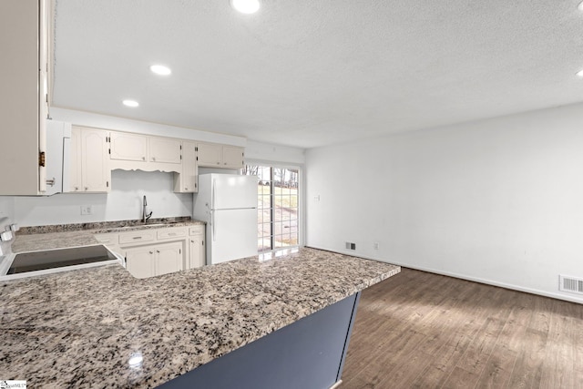 kitchen featuring sink, dark hardwood / wood-style flooring, white refrigerator, stove, and a textured ceiling