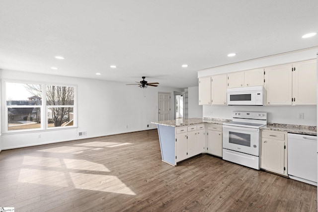 kitchen with light stone counters, white appliances, wood-type flooring, and white cabinets