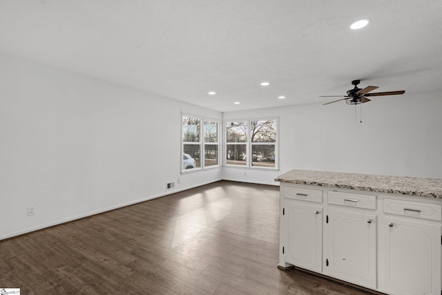 interior space featuring white cabinetry, dark wood-type flooring, ceiling fan, and light stone counters