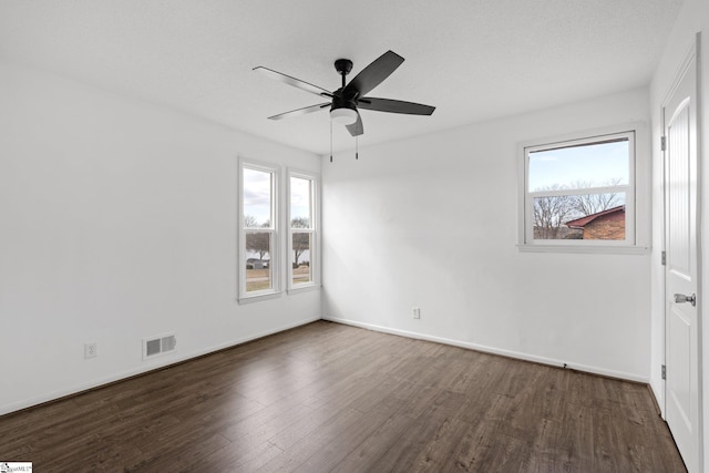 spare room featuring ceiling fan, a textured ceiling, dark wood-type flooring, and a healthy amount of sunlight