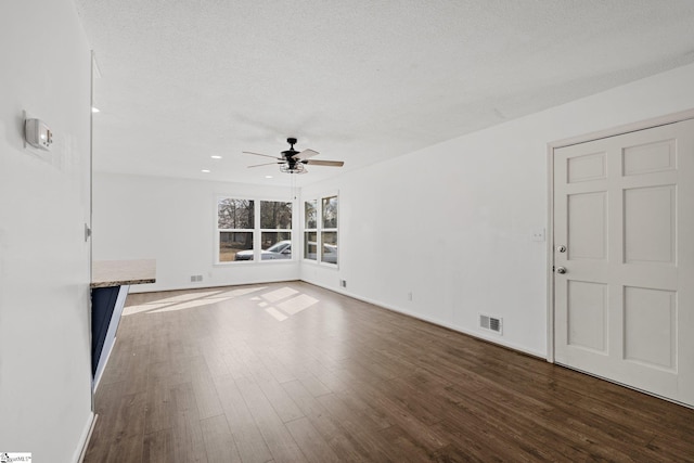 unfurnished living room with ceiling fan, a textured ceiling, and dark hardwood / wood-style flooring