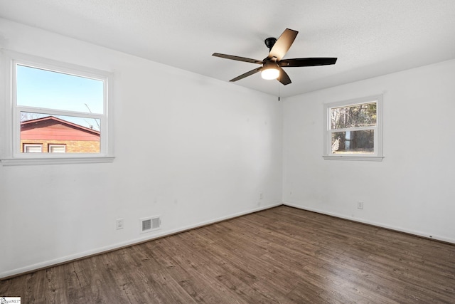 spare room featuring dark wood-type flooring, a wealth of natural light, and ceiling fan