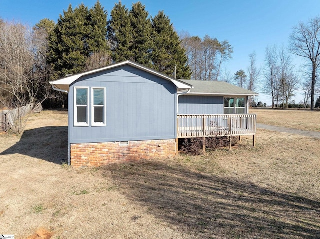 view of side of home with a wooden deck and a yard