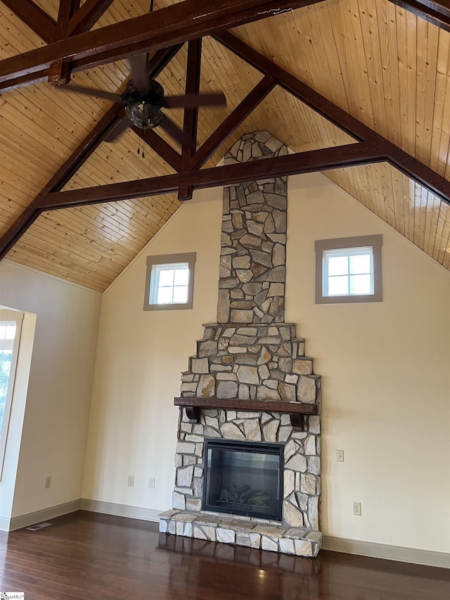 unfurnished living room with beamed ceiling, wood ceiling, wood-type flooring, and a stone fireplace