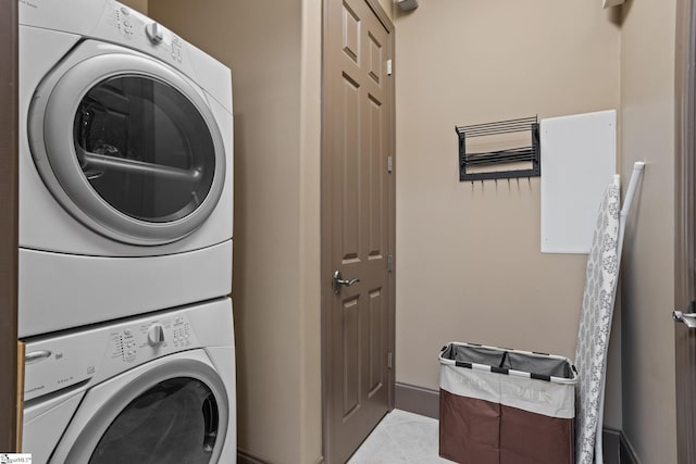 laundry room with stacked washer / drying machine and light tile patterned floors