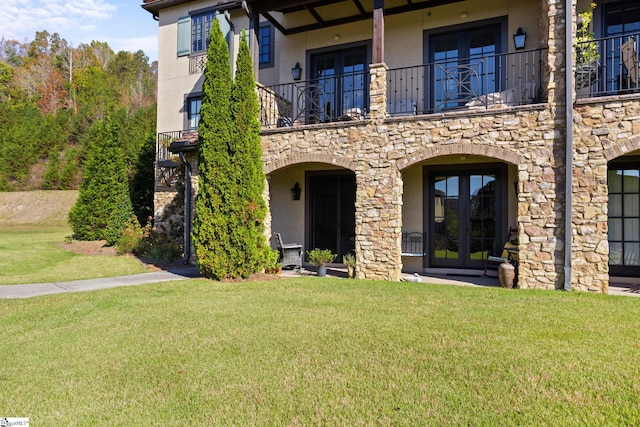 exterior space with french doors, a balcony, and a yard