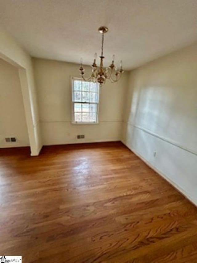 unfurnished dining area with an inviting chandelier and wood-type flooring